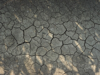 Cracked soil caused by the heat of the sun texture background, close up. Dry land requires rain water. Top view. Drought in nature is very harmful. Summer in Italy.