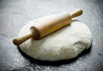 Freshly prepared dough with a rolling pin.