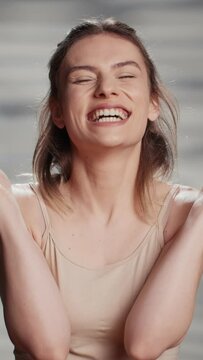 Vertical video: Happy cheerful person laughing with cotton pads on camera, using accessories to promote skincare routine and self confidence. Young beautiful model acting positive and silly for ad.
