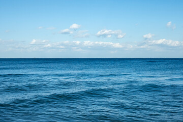 The water ripples in the sea against the backdrop of a cloudy blue sky. The color of the blue sky...