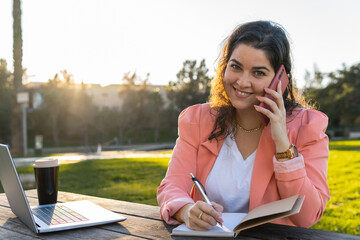 Young businesswoman talking on the phone writing notes.