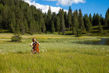 Woman plays the cello on a hot summer day in the middle of a meadow © alexandre zveiger