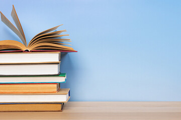 Composition with vintage old hardback books, diary and open book whith old pages on wooden table and blue background. Books stacking. Back to school. Copy Space. Education background.