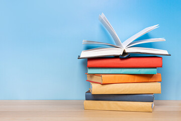 Composition with vintage old hardback books, diary and open book whith old pages on wooden table and blue background. Books stacking. Back to school. Copy Space. Education background.