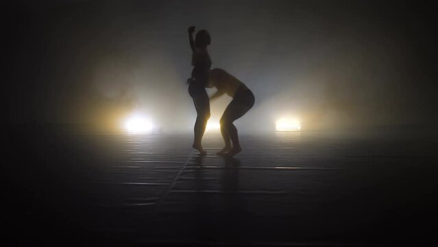 Romantic professional ballet pair practicing moves on dark stage