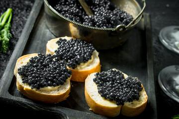 Sandwiches with black caviar on the cutting Board.