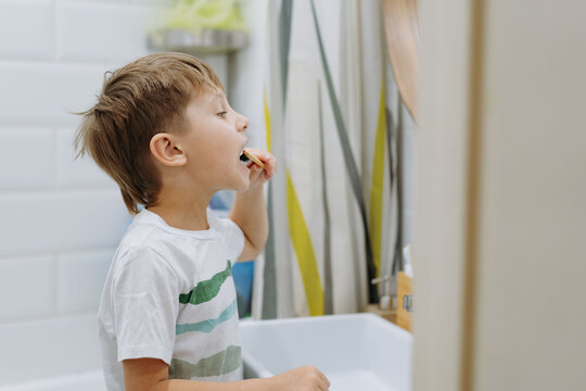 cute 5 years old boy brushing teeth with bamboo tooth brush in bathroom. Image with selective focus