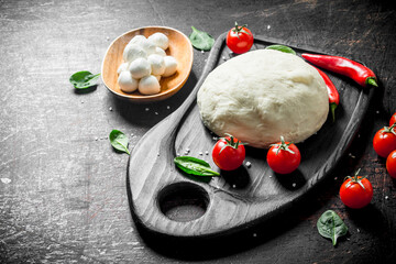 Dough with tomatoes, chili pepper and mozzarella.
