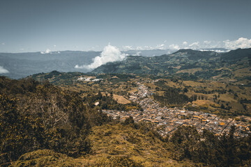 Wide panorama of the colonial village (pueblo) of Jerico (Jericó), Antioquia, Colombia, with a blue sky and the Andes Mountains in the background. From the Cerro las Nubes (Mount of the Clouds).