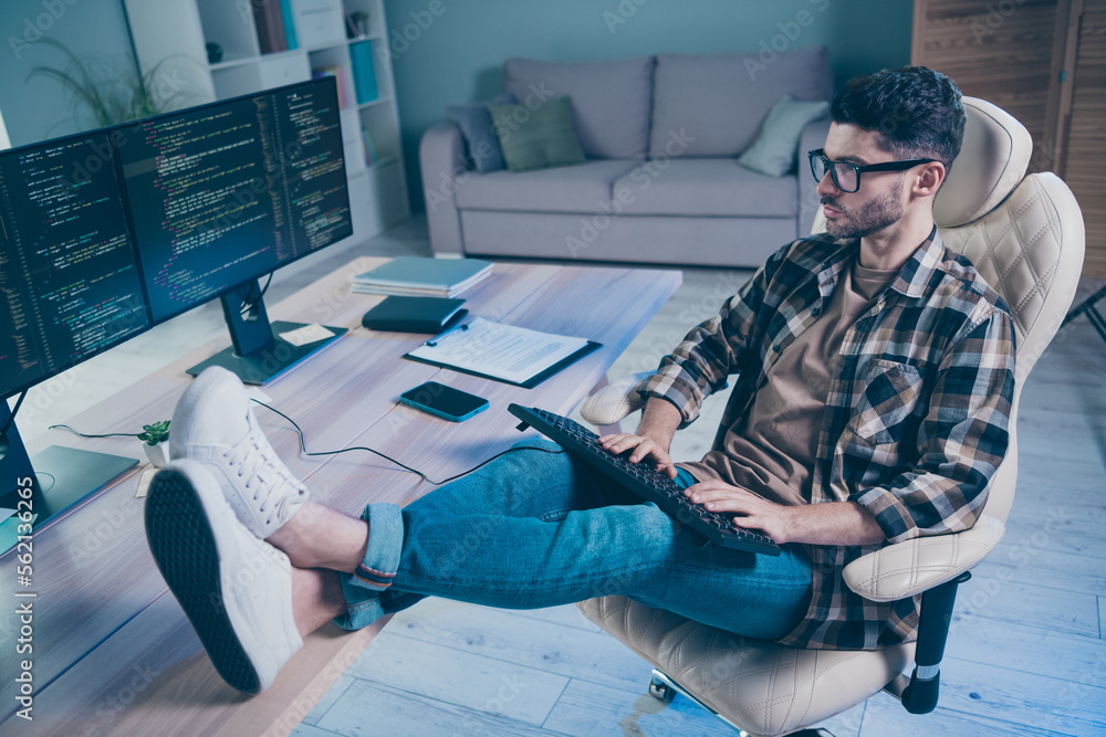 Poster full length photo of focused experienced pc operator man sit chair keyboard write code put legs tabl