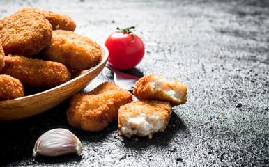 Chicken nuggets in a bowl and pieces of nuggets.