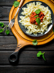 Farfalle pasta with Bolognese sauce and mint leaves on a plate.