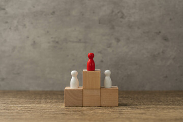 Concept of difference and leadership. White wooden puppets arranged in a circle, but one of them is...