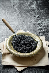 Black caviar in a bowl on paper.