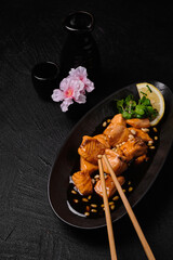 Bottle of sake, cups and salmon in teriyaki sauce