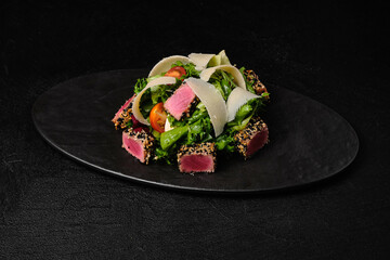 Tuna salad with parmesan on black plate