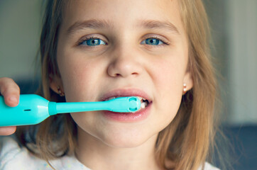 Close-up of a little girl brushing her teeth with an electric toothbrush. The concept of modern oral care, morning or evening care for teeth and gums