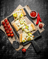 Slices of vegetable pizza with cherry tomatoes and sauce in bowl.