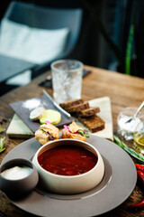 Beetroot soup Borscht with meat and sourcream in a bowl. Delicious healthy Ukrainian traditional food closeup served for lunch on a table in modern gourmet cuisine restaurant