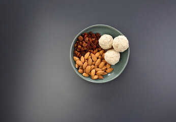 Energy balls from almonds and raisins in a round bowl on a gray background. A simple and healthy snack.