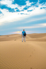 Fototapeta na wymiar One man stands on a sand dune in the Kyzylkum desert at sunrise.