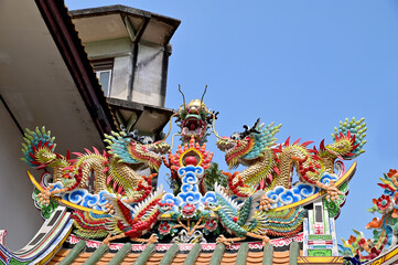 The Double Chinese dragons on the temple roof with blue sky background at Chinese Temple, Thailand