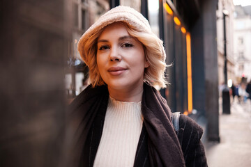 Urban portrait of young woman with orange neon light behind her.