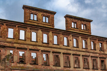 Fototapeta premium Close-up view of the façade ruin of the former residential palace called Englischer Bau with its stucco decorated window fronts rising high into the cloudy blue sky, a part of the Heidelberger Castle.