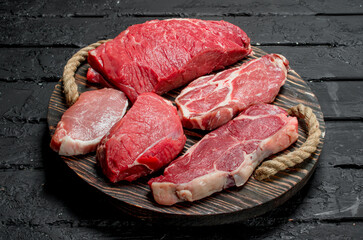 Raw meat. Beef and pork steaks on a wooden tray.