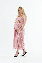 A pregnant woman in a white transparent dress embraces her stomach with her hands. Place for the text. White background.