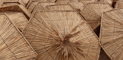 Straw beach umbrellas are stacked as an abstract background.