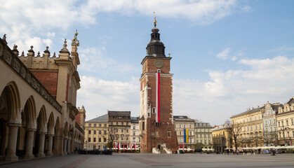 Fototapeta na wymiar Town Hall Tower (Wieża Ratuszowa) and Cloth Hall (Sukiennice Kraków) on Main Market Square in the Old Town Krakow, Poland. Decorated with Polish flag for celebration of 3 May Constitution Day.