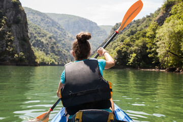 Attractive female kayaking. Girl enjoying a ride on a mountain river.