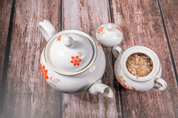 Old retro coffee set with coffee pot and sugar bowl filled with candy in floral design on the porcelain