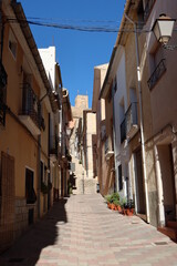 Fototapeta na wymiar Biar, Alicante, Spain, January 14, 2023: Narrow street with the castle in the background in Biar, Alicante, Spain