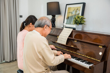 Family care. Asian young woman teaching piano for senior man teaching, happy daughter and elderly...