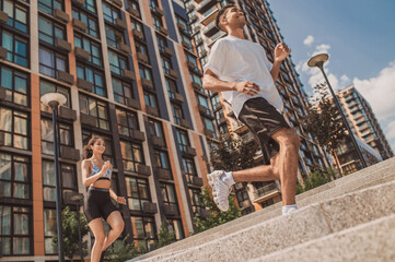 Athletic guy and a fit girl running together outdoors