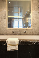 Modern design black and white marble bathroom with sink, whirlpool bath tub, shower, towels and...