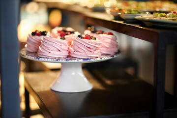 Pink berry meringue with fresh berries on a white stand. Confectionery. 
