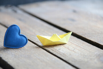 Blue heart on a wooden background and paper boat. Place for text. Valentine. Birthday background.