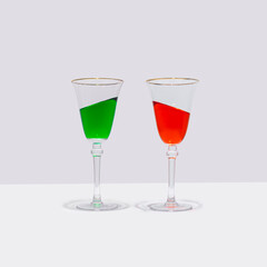 Two colorful cocktail glasses stand straight with the drink in them at an inclined angle. Surreal drinking culture, summer party or celebration composition.