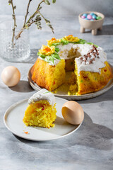 Easter cake decorated with icing and spring flowers with Easter eggs and willow twigs on gray background. Happy easter holiday.