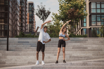 Cheerful couple performing a stretching exercise on the steps