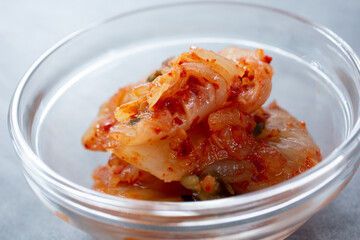 A closeup view of a glass condiment cup of kimchi. 