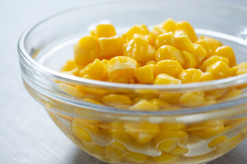 A closeup view of a glass condiment cup of canned corn kernels.