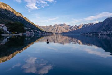 Naklejka na ściany i meble Panoramic view of bay of Kotor at sunrise in summer, Adriatic Mediterranean Sea, Montenegro, Balkans, Europe. Fjord winding along coastal towns. First sunbeams on Lovcen mountains. Water reflection