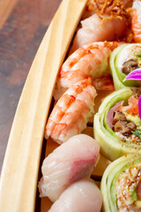 A view of a portion of a sushi boat, featuring nigiri pieces and cucumber rolls.