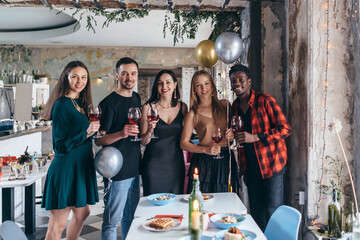 People enjoying drinks at cafe. Friends at bar toasting wine and smiling