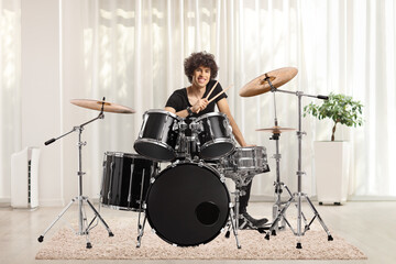 Fototapeta premium Young male drummer holding drumsticks and smiling in a room