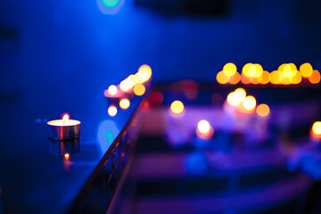 Tea candle and defocused candle lights on blue background